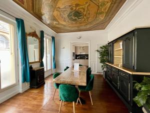 a dining room with a table and green chairs at Appartement de luxe avec fresque, hyper centre et parking sûre in Fontainebleau