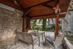 a patio with chairs and a table and a stone wall at Villa Palma in Kotor