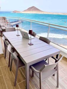 a table with chairs and a laptop on a balcony at Grand appartement de standing avec vue sur mer à Medano, Tenerife sud in La Tejita
