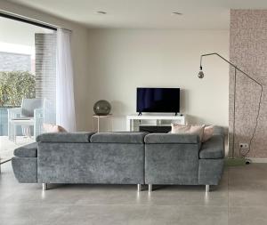 a living room with a couch and a tv at Design Apartment with 60m² terrace - heated inside pool and wellness facilities - very close to the beach in Cadzand