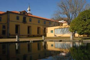 a yellow building with a reflection in a body of water at Casa do Mosteiro de Refoios do Lima in Ponte de Lima