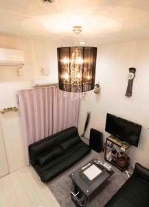 sala de estar con sofá negro y lámpara de araña en Designer's apartment polaris 101 - Vacation STAY 13314, en Nagoya