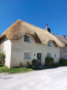 a thatched house with a thatched roof at Stable Cottage - near Lulworth Cove in Dorchester