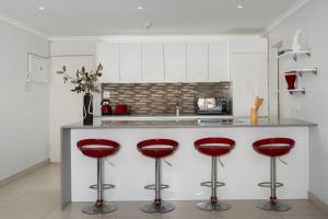 a kitchen with red stools at a counter at 220 On Loop Luxury Apartments in Cape Town