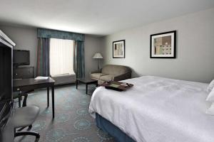 a hotel room with a bed and a couch and a desk at Hampton Inn Defiance in Defiance