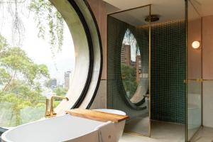 a bathroom with a tub and a large window at 23 Hotel Medellin in Medellín