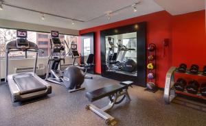 a gym with cardio equipment in a room with red walls at DoubleTree by Hilton Orange County Airport in Santa Ana