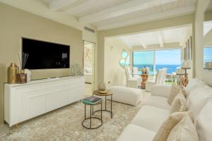 Una sala de estar con un sofá blanco y un televisor. en Villa con vista da sogno, en Porto Cervo