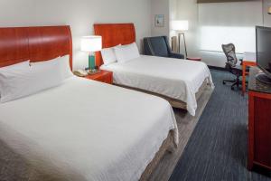 a hotel room with two beds and a flat screen tv at Hilton Garden Inn Plymouth in Plymouth