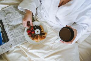 a woman in bed with a plate of food and a cup of coffee at Louisa's Place in Berlin