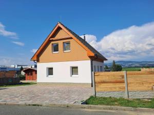 a white and orange house with a wooden fence at Chata Štíty in Štíty