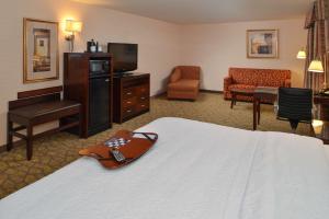 a hotel room with a bed and a television and a chair at Hampton Inn & Suites Tacoma in Tacoma