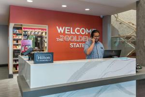 un hombre hablando por un celular en una bienvenida a la tienda estatal dorada en Hampton Inn Oakland Downtown-City Center, en Oakland