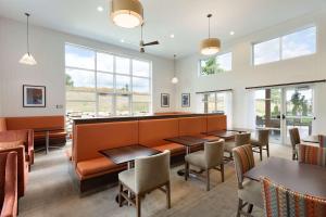 un restaurant avec des tables, des chaises et des fenêtres dans l'établissement Homewood Suites by Hilton Gateway Hills Nashua, à Nashua