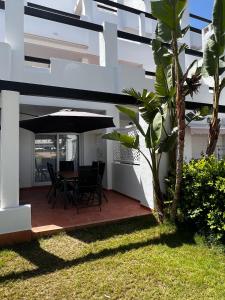 une terrasse avec une table, des chaises et un parasol dans l'établissement Las Terrazas De La Torre Golf Resort, à Las Pedreñas