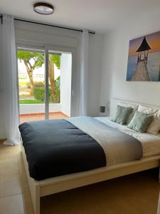 - une chambre avec un grand lit et une grande fenêtre dans l'établissement Las Terrazas De La Torre Golf Resort, à Las Pedreñas