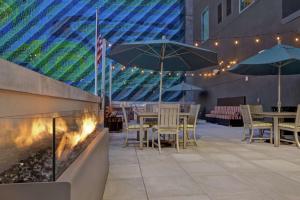 a restaurant with tables and umbrellas and a fire place at Home2 Suites By Hilton Charlotte Uptown in Charlotte