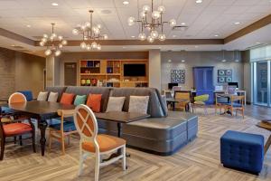 a lobby with a couch and tables and chairs at Home2 Suites By Hilton Charlotte Uptown in Charlotte