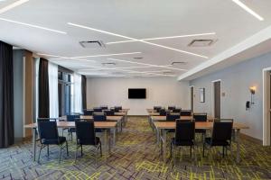 una sala de conferencias con mesas, sillas y una pantalla en Home2 Suites By Hilton Charlotte Uptown, en Charlotte