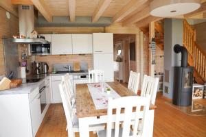 a kitchen with white cabinets and a table and chairs at Haus am See mit Privatstrand, Kamin und Sauna in Löbnitz