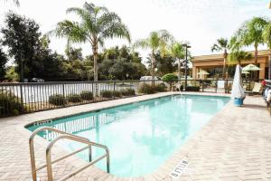 een groot zwembad met een hek en palmbomen bij Hampton Inn & Suites Ocala - Belleview in Marion Oaks