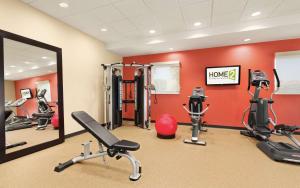 une salle de sport avec des appareils d'exercice et un mur rouge dans l'établissement Home2 Suites St. Louis / Forest Park, à Richmond Heights