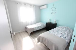 2 letti in una camera da letto con pareti blu e finestra di Maison climatisée avec parking a Montauban