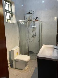 ein Bad mit einer Dusche, einem WC und einem Waschbecken in der Unterkunft Best House Kimironko in Kigali