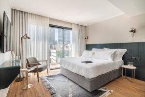 um quarto de hotel com uma cama e uma grande janela em Jo Shtibel Tel-Aviv em Tel Aviv