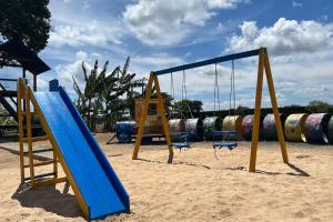 une aire de jeux avec une balançoire bleue installée dans le sable dans l'établissement Casa Retrô Chique Bananeiras - Cond Yes Banana, à Bananeiras