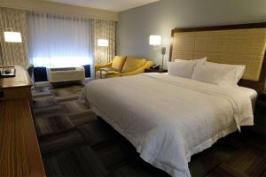 una habitación de hotel con una cama grande y una silla en Hampton Inn Searcy Arkansas en Searcy