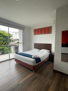 a bedroom with a bed and a large window at Ayenda Apartamento Turistico Distrito 9 90 in Cali