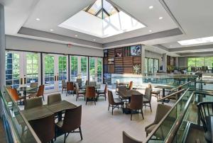 un restaurante con mesas, sillas y ventanas en Hilton Peachtree City Atlanta Hotel & Conference Center, en Peachtree City