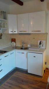 uma cozinha com armários brancos e um lavatório em Kolombo Apartment em Jadrija