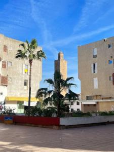 duas palmeiras em frente a dois edifícios em Appartement hay el fath résidence calme propre em Rabat