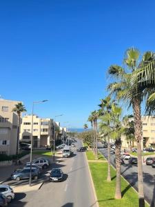 uma rua da cidade com palmeiras e carros na estrada em Appartement hay el fath résidence calme propre em Rabat