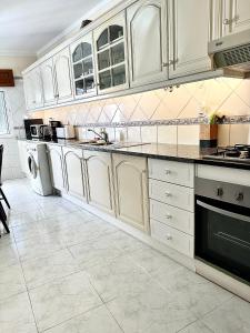 a kitchen with white cabinets and a tile floor at Rei Apartment in Quarteira