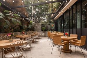 un restaurante con mesas de madera, sillas y plantas en 23 Hotel Medellin, en Medellín