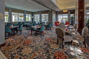 uma sala de jantar com mesas, cadeiras e janelas em Hilton Garden Inn Midtown Tulsa em Tulsa