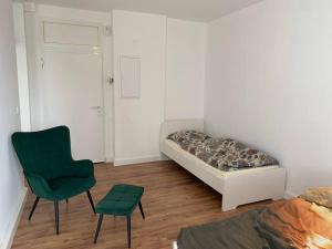 a bedroom with a bed and a green chair at Monteur- & Ferienwohnungen in Dorsten Altstadt - ZENTRUM - NEU saniert in Dorsten