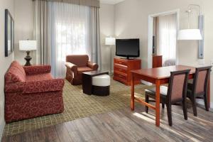 a living room with a table and a chair and a television at Homewood Suites by Hilton Tallahassee in Tallahassee