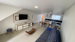 sala de estar con sofá azul y cocina en Apto 03 Quartos frente mar, en Porto Seguro