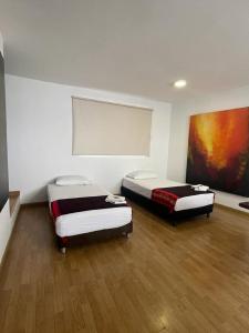two beds in a room with a painting on the wall at Ayenda Apartamento Turistico Distrito 9 90 in Cali