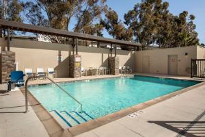 a swimming pool at a resort with chairs and tables at Home2 Suites By Hilton Redlands in Redlands