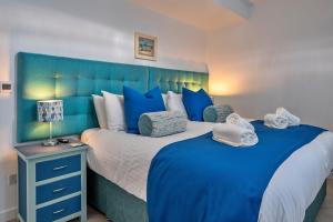 1 dormitorio con 2 camas y cabecero azul en Finest Retreats - Lobster House, en Newquay