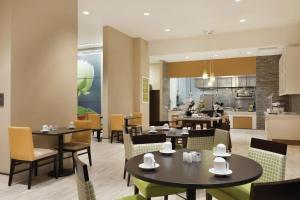 a restaurant with tables and chairs and a kitchen at Hilton Garden Inn Rochester Downtown, NY in Rochester