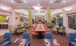 Hilton Garden Inn Des Moines/Urbandale في Urbandale: غرفة طعام طويلة مع طاولات وكراسي