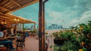 a patio with people sitting at tables in a restaurant at Fatima Hostel Santa Marta in Santa Marta