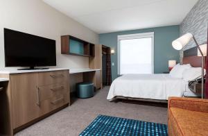 a bedroom with a bed and a flat screen tv at Home2 Suites By Hilton Roswell, Ga in Roswell