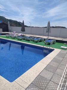 a swimming pool with chairs and umbrellas on the side at Retiro da Estrela in Seia